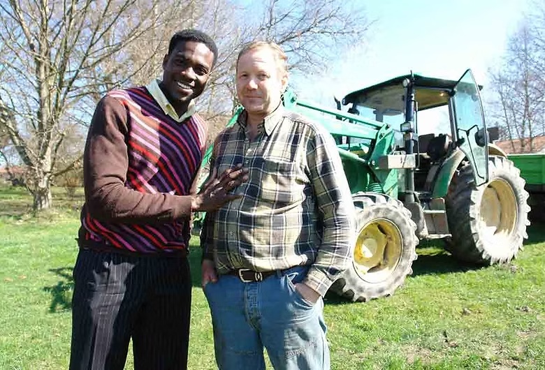 Joseph Renwick Randon with a local partner near a tractor during the New Millennium Mission Tour